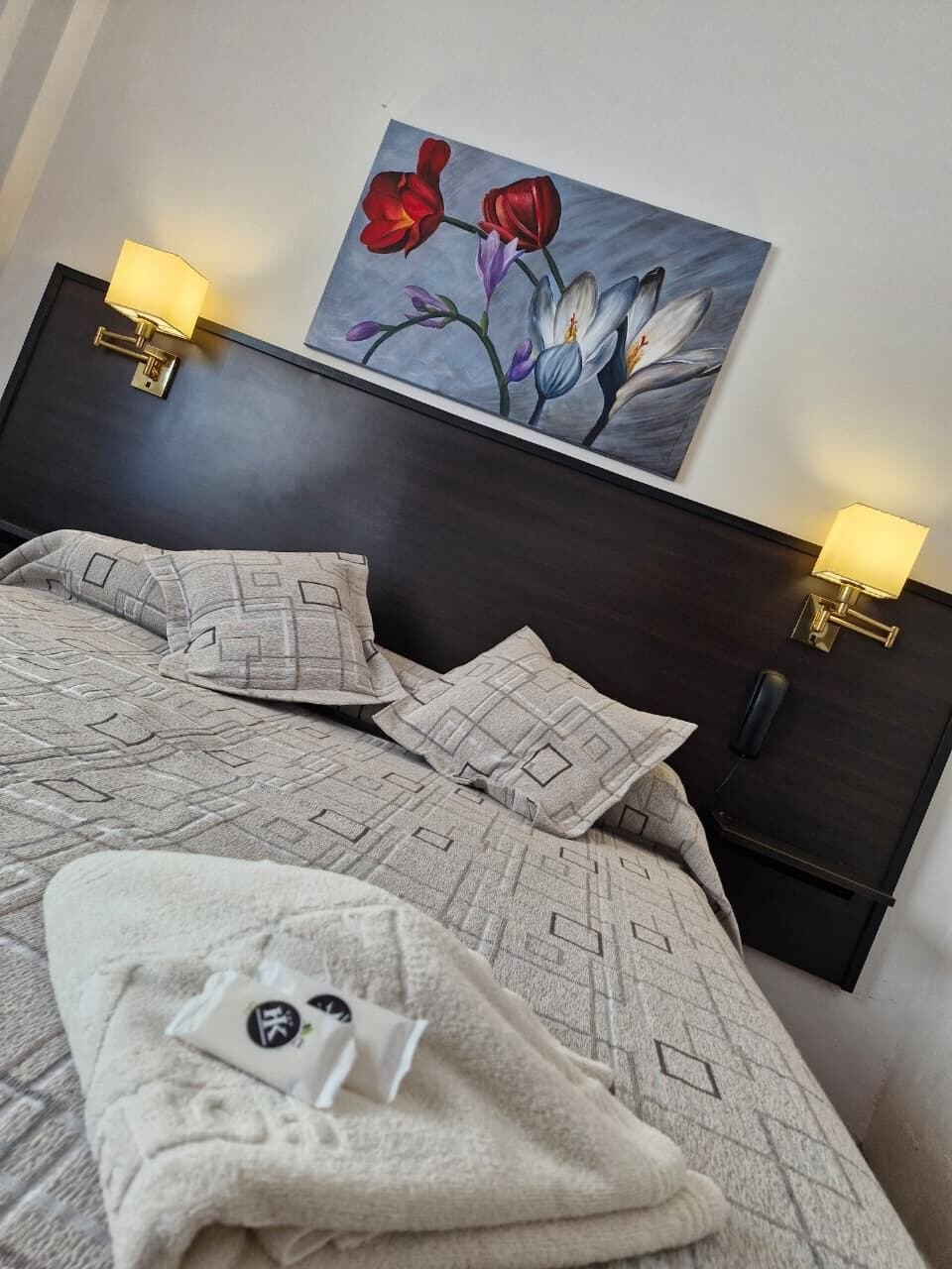 Toalla y jaboncitos con el logo HK sobre la cama